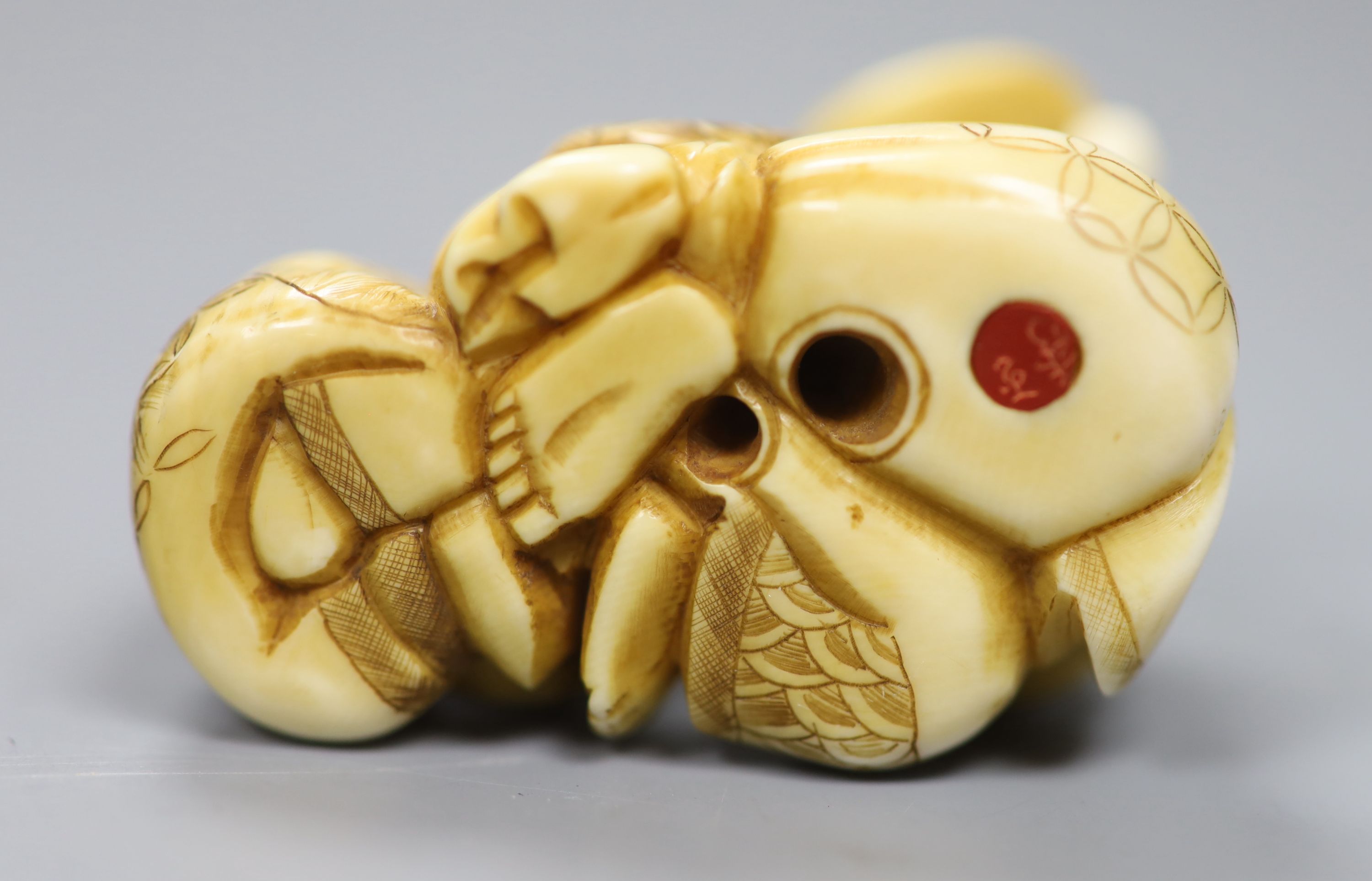 A Japanese ivory netsuke in the form of a seated Hotei and attendant, early 20th century 3cm high, 5cm wide, signed to underside, toget